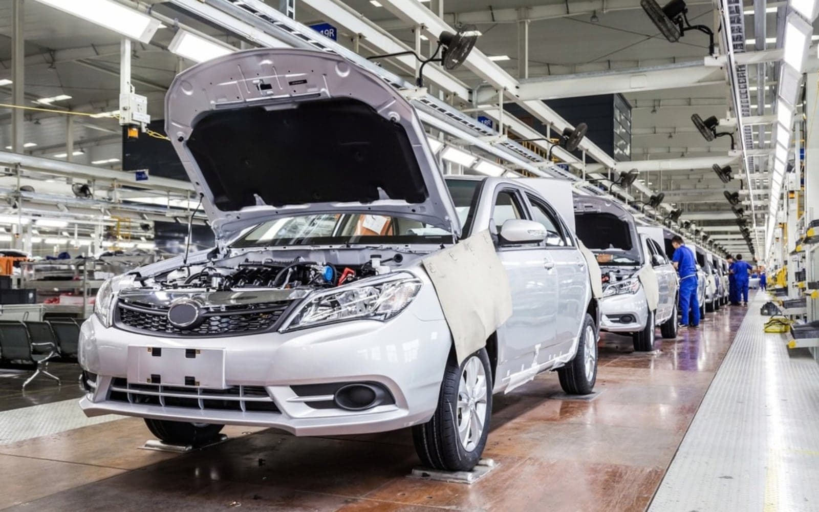 Cars on an automotive assembly line with bonnets open for inspection